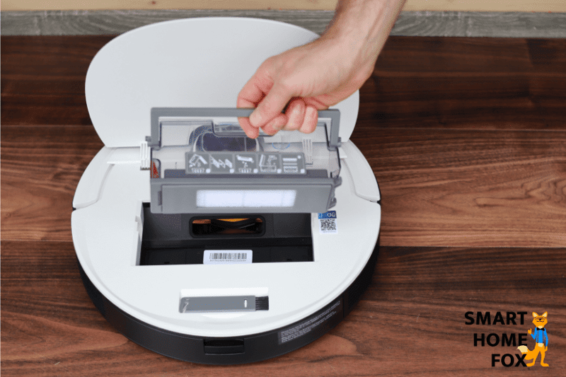 Ecovacs Deebot T8 steht mit offener Klappe da und der Staubbehälter wird entnommen